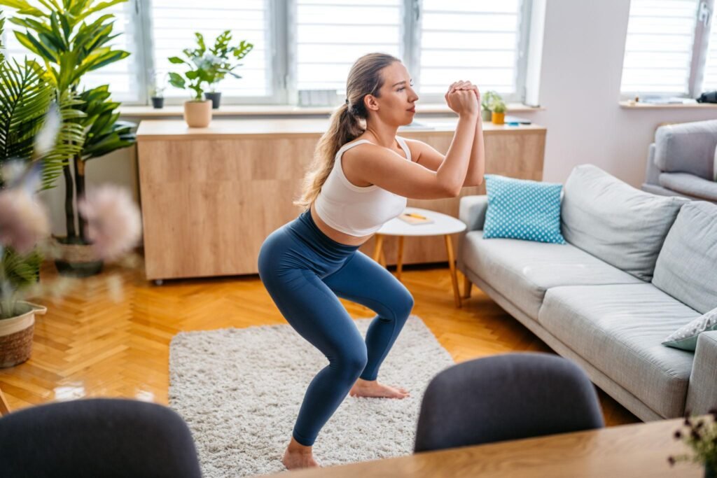 Woman doing home workout squats in a bright minimalist living room for strength training and fitness
