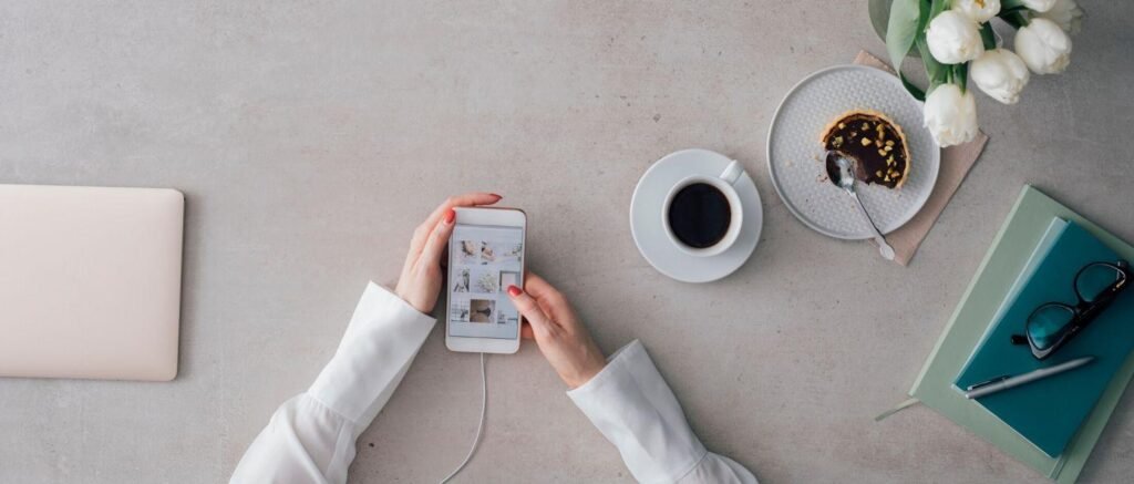 Woman using smartphone beside laptop and coffee